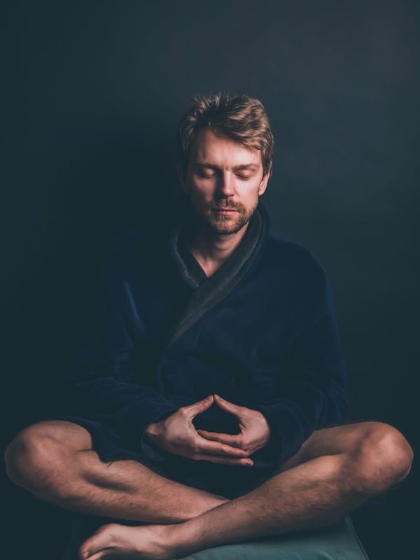 Man sitting in a calm cross-legged pose with eyes closed.